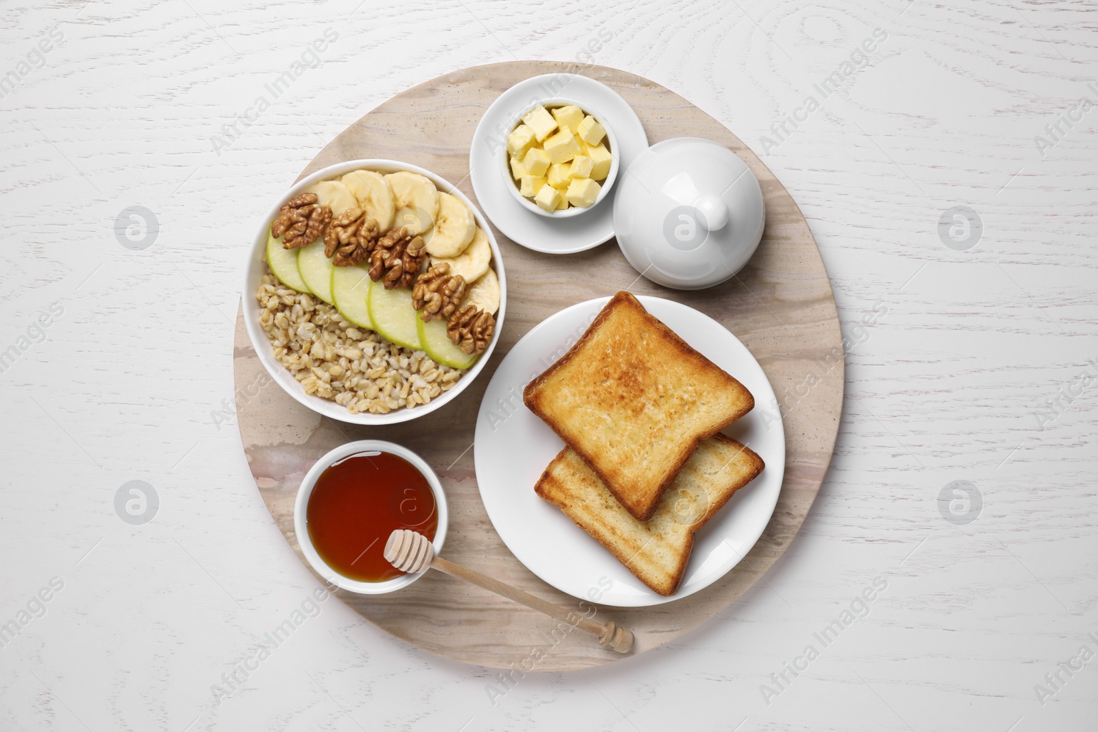 Photo of Tasty breakfast with oatmeal porridge and toasts served on white wooden table, top view