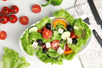 Tasty fresh Greek salad on white table, flat lay