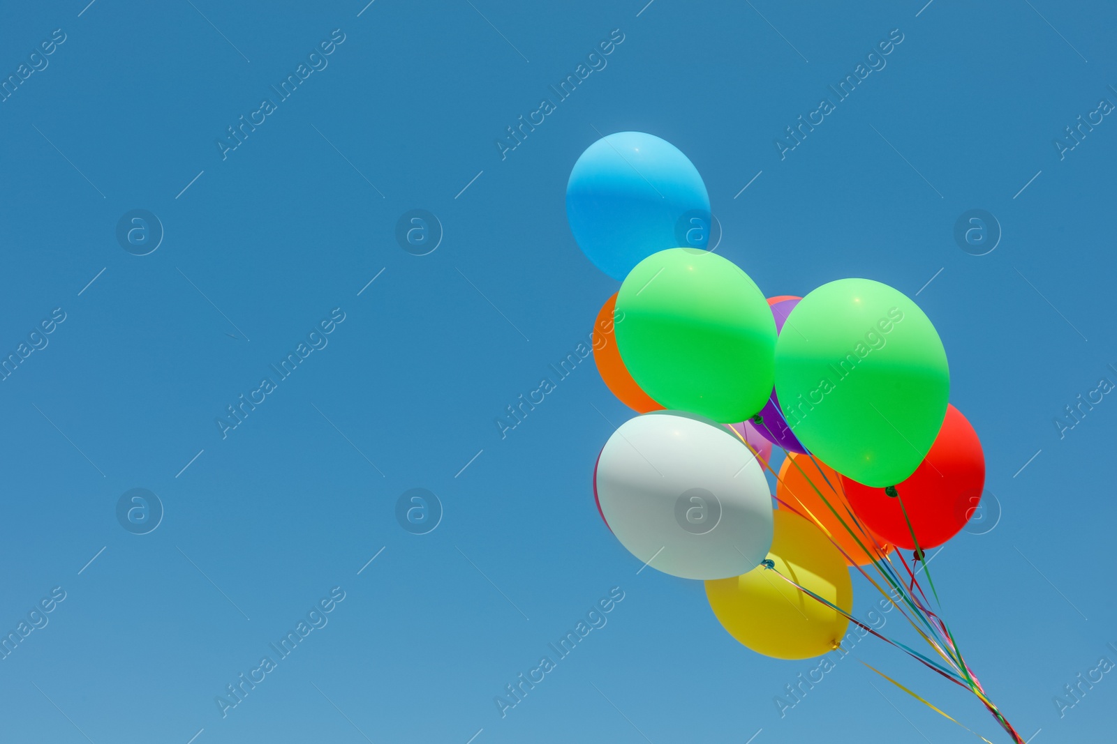 Photo of Bunch of colorful balloons against blue sky. Space for text