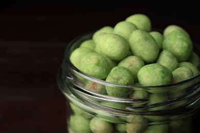 Tasty wasabi coated peanuts in glass jar, closeup