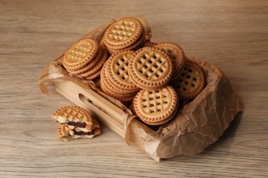 Tasty sandwich cookies with cream on wooden table