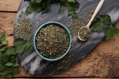 Photo of Dried parsley and fresh leaves on wooden table, flat lay