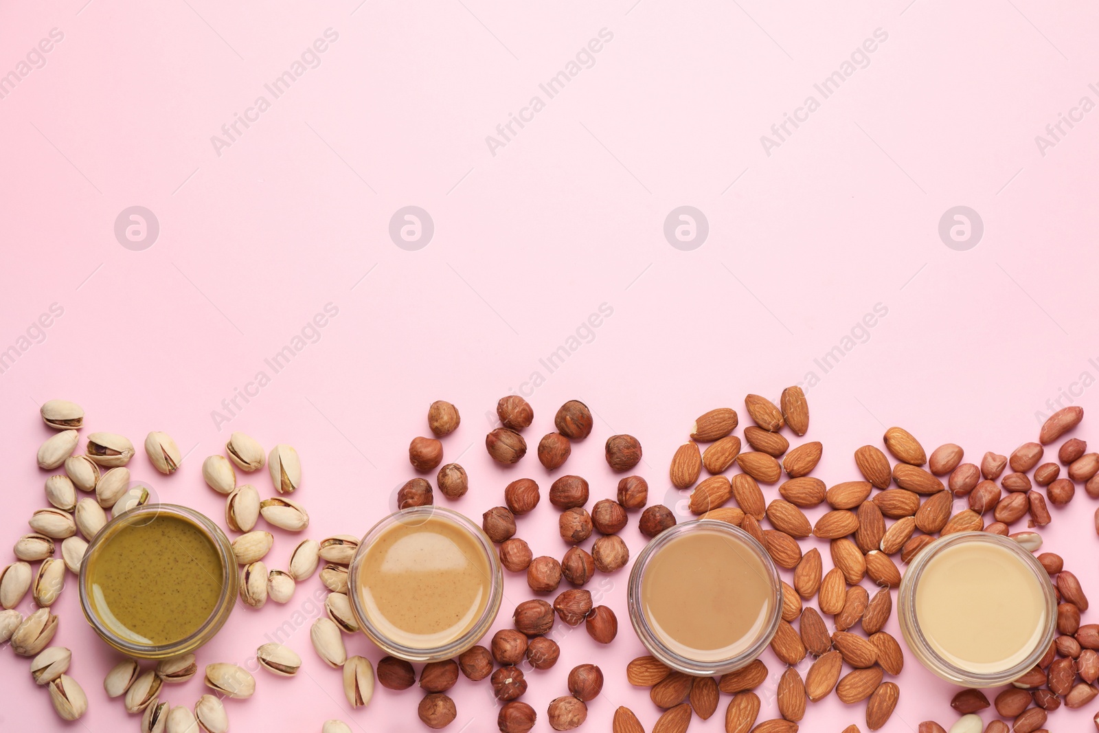 Photo of Different types of delicious nut butters and ingredients on pink background, flat lay. Space for text