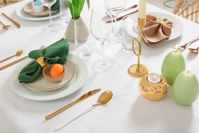 Photo of Festive Easter table setting with painted eggs and burning candles