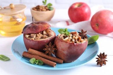 Photo of Tasty baked apples with nuts, honey, spices and mint on white wooden table