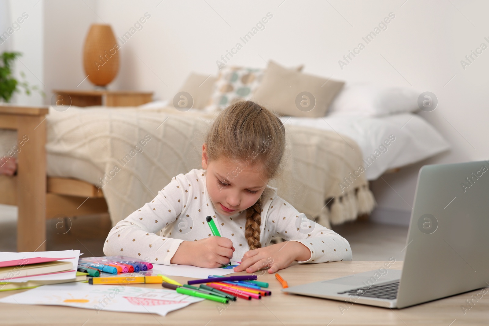 Photo of Little girl drawing with felt-tip pen following online course at home. Time for hobby