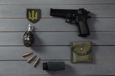 Photo of MYKOLAIV, UKRAINE - SEPTEMBER 26, 2020: Frame made of tactical gear and Ukrainian army patch on grey wooden table, flat lay. Space for text