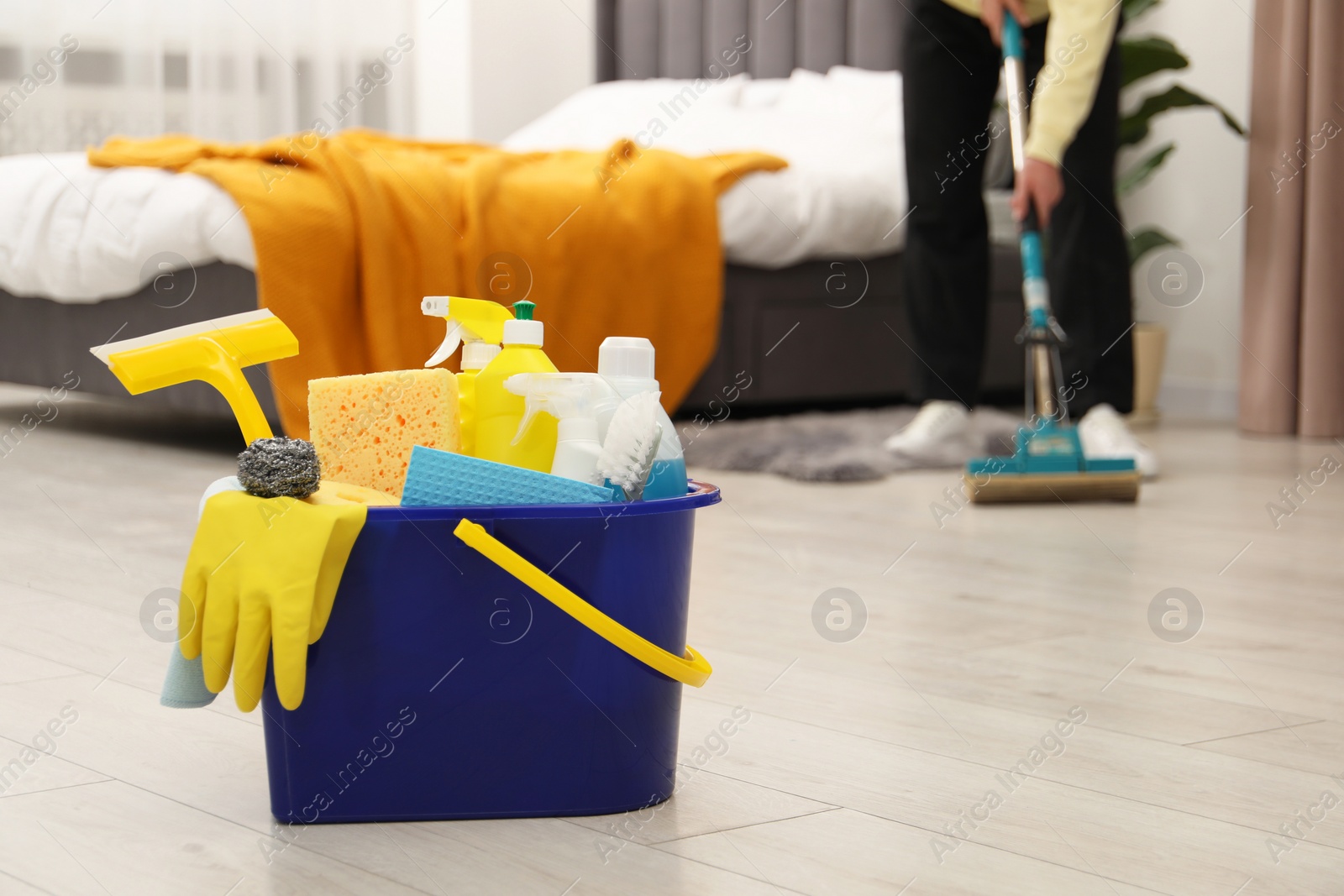 Photo of Woman cleaning floor, focus on different supplies in bucket at home