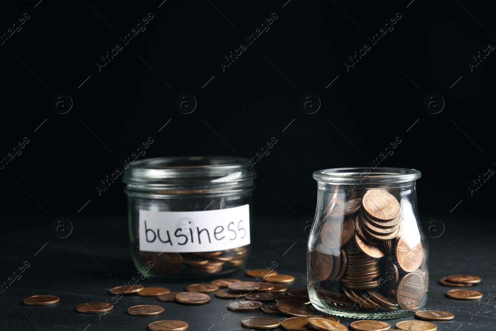 Photo of Glass jars with coins and tag BUSINESS on black table