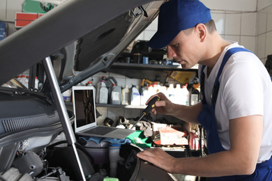 Mechanic with laptop doing car diagnostic at automobile repair shop