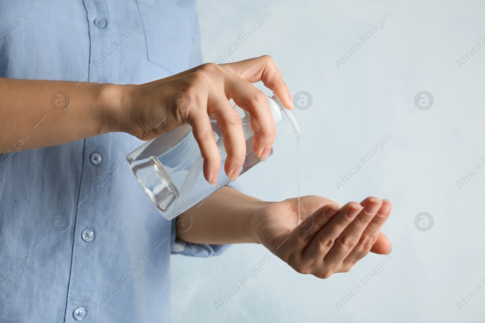 Photo of Woman applying antiseptic gel onto hand against light background, closeup. Virus prevention