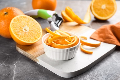 Photo of Orange fruits with peel on grey marble table