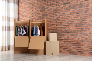 Wardrobe boxes with clothes against brick wall indoors. Space for text