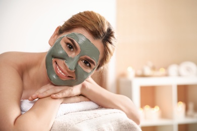 Beautiful woman with mask on face relaxing in spa salon. Space for text