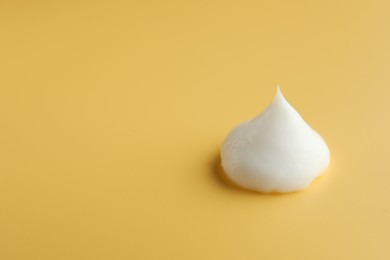 Photo of Sample of face cream on yellow background, space for text