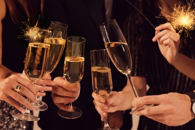 Photo of Friends clinking glasses of sparkling wine, closeup. New Year celebration