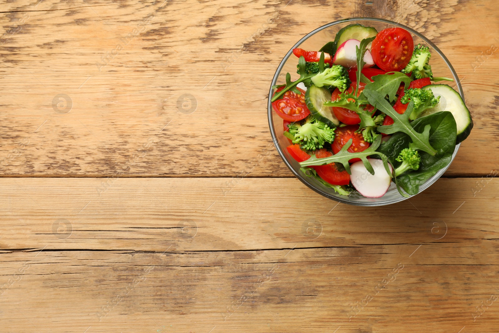 Photo of Tasty fresh vegetarian salad on wooden table, top view. Space for text