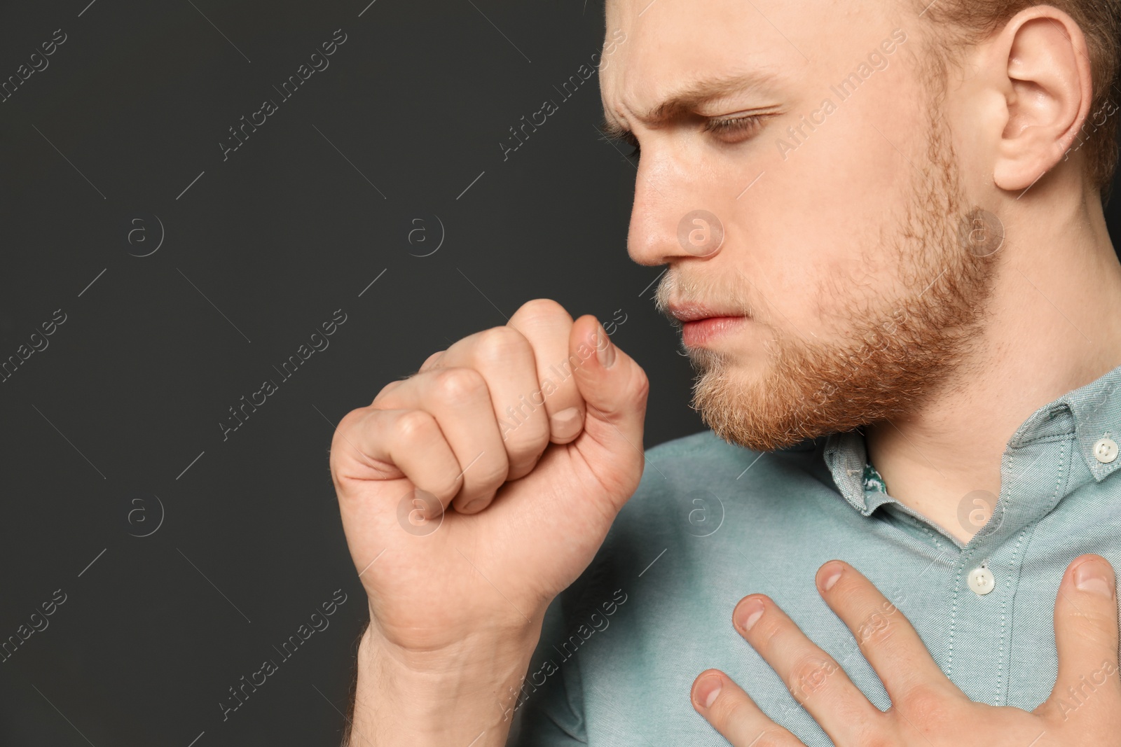 Photo of Handsome young man coughing against dark background. Space for text