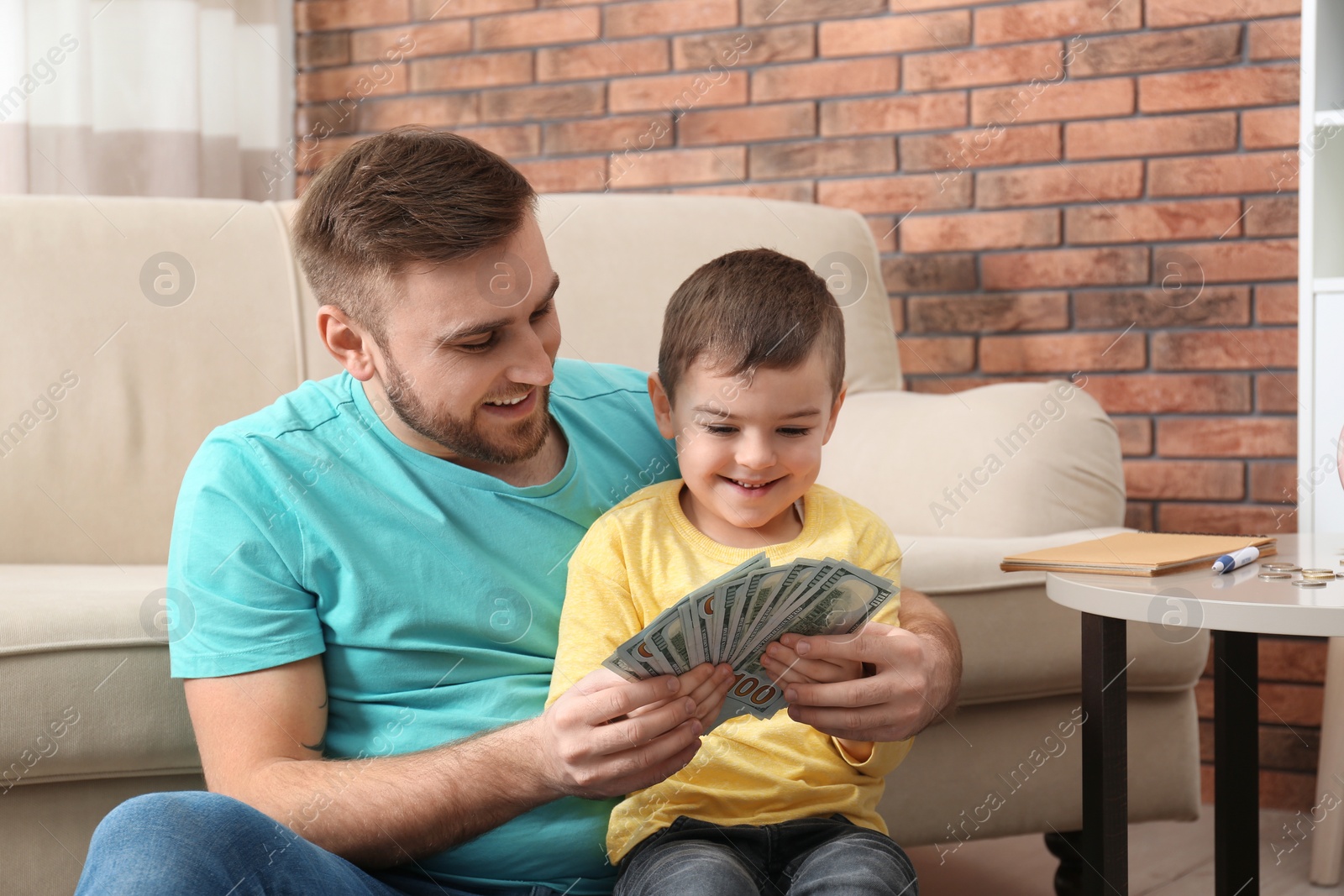 Photo of Happy father and son with money at home