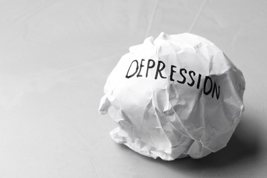 Photo of Crumpled paper ball with written word Depression on light background. Space for text