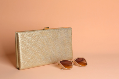 Photo of Stylish woman's bag and sunglasses on pale pink background