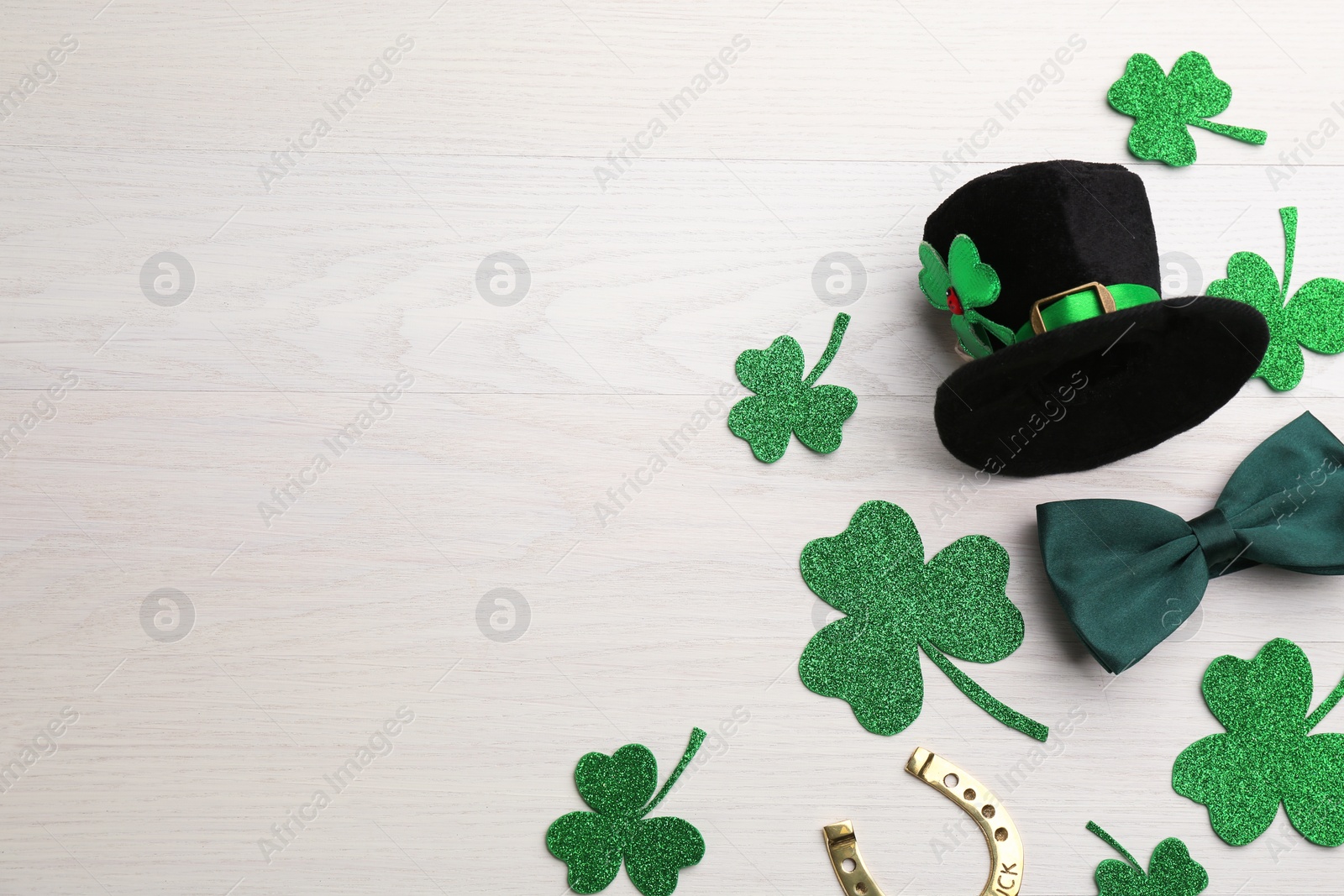 Photo of Flat lay composition with leprechaun hat on white wooden table, space for text. St Patrick's Day celebration