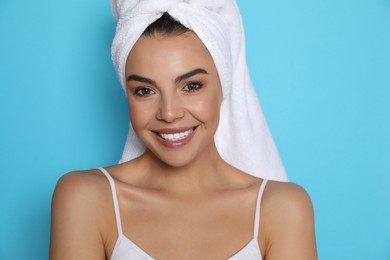 Photo of Beautiful young woman with towel on head against light blue background