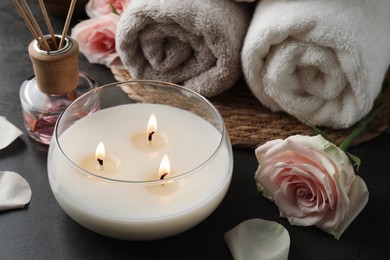 Spa composition with burning candle and towels on grey table, closeup