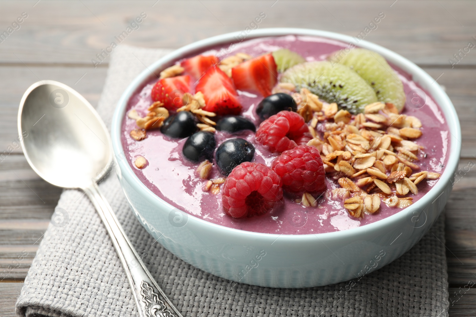 Photo of Delicious acai smoothie with fruits served on grey wooden table, closeup