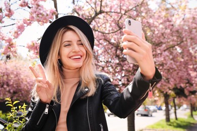 Photo of Happy woman taking selfie outdoors on spring day