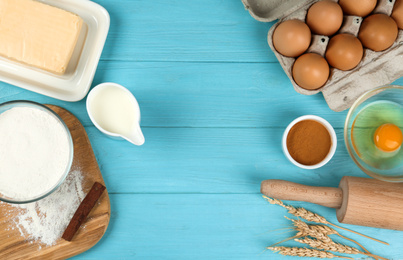 Photo of Flat lay composition with eggs and other ingredients on light blue wooden table, space for text. Baking pie