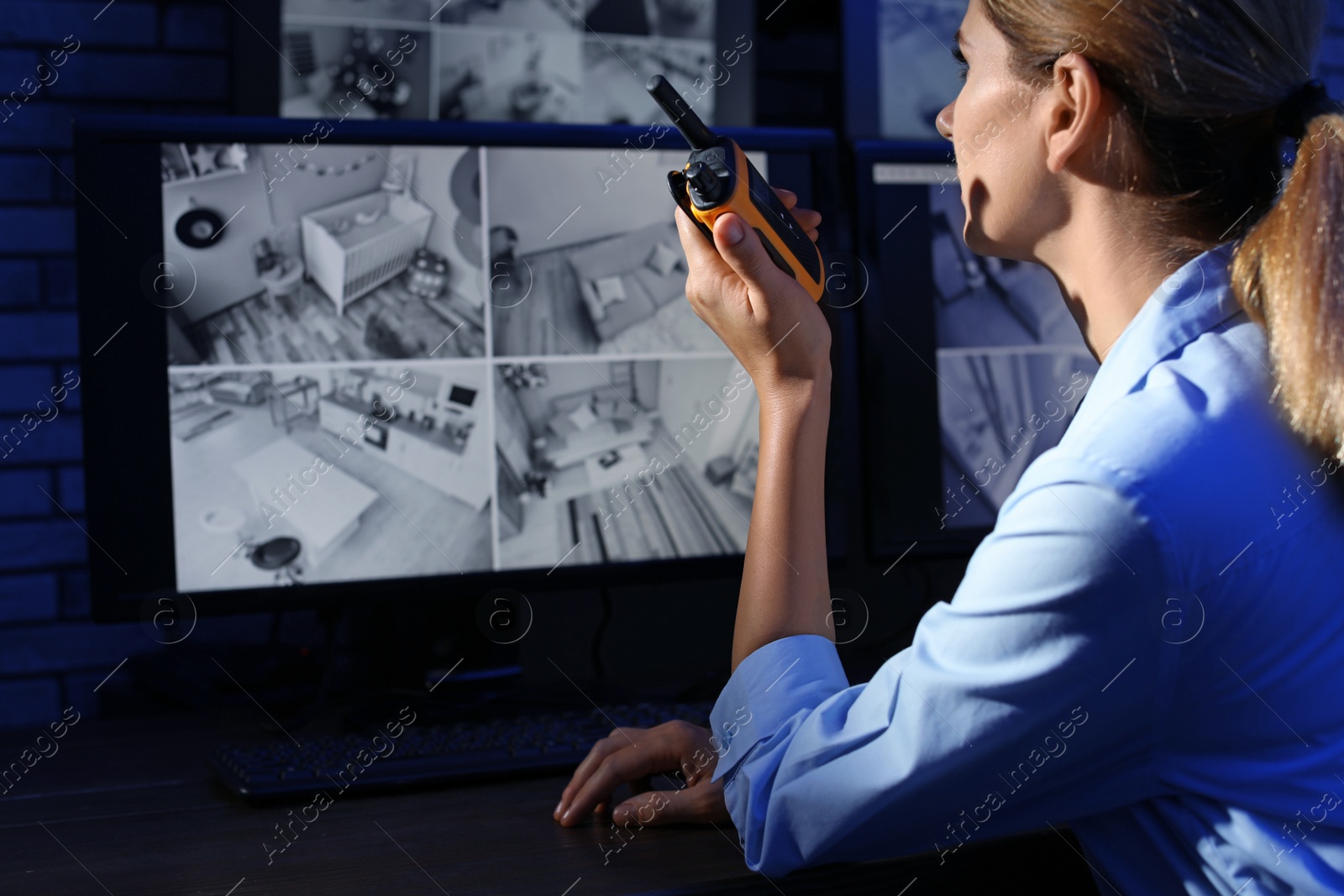 Photo of Female security guard with portable transmitter monitoring modern CCTV cameras indoors