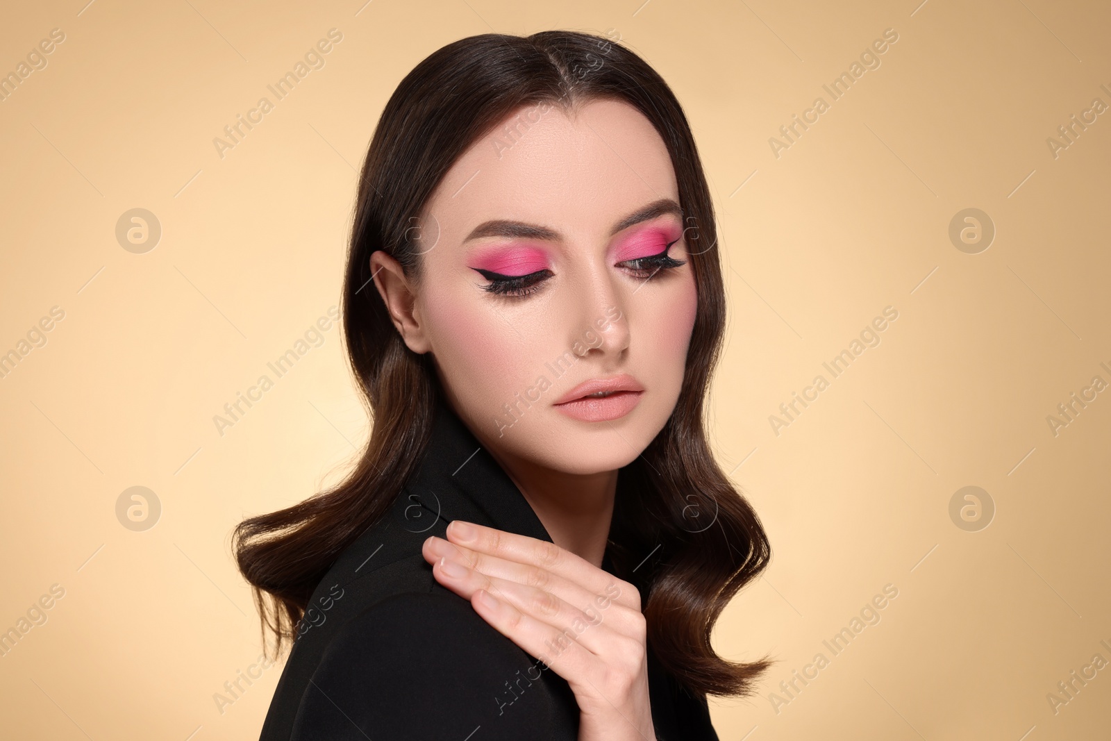 Photo of Portrait of beautiful young woman with makeup and gorgeous hair styling on beige background