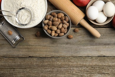 Photo of Nutmeg seeds and other ingredients on wooden table, flat lay. Space for text