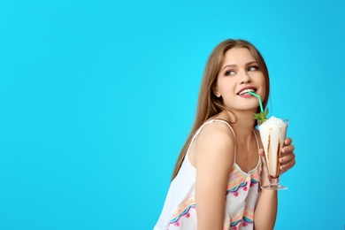 Photo of Young woman with glass of delicious milk shake on color background