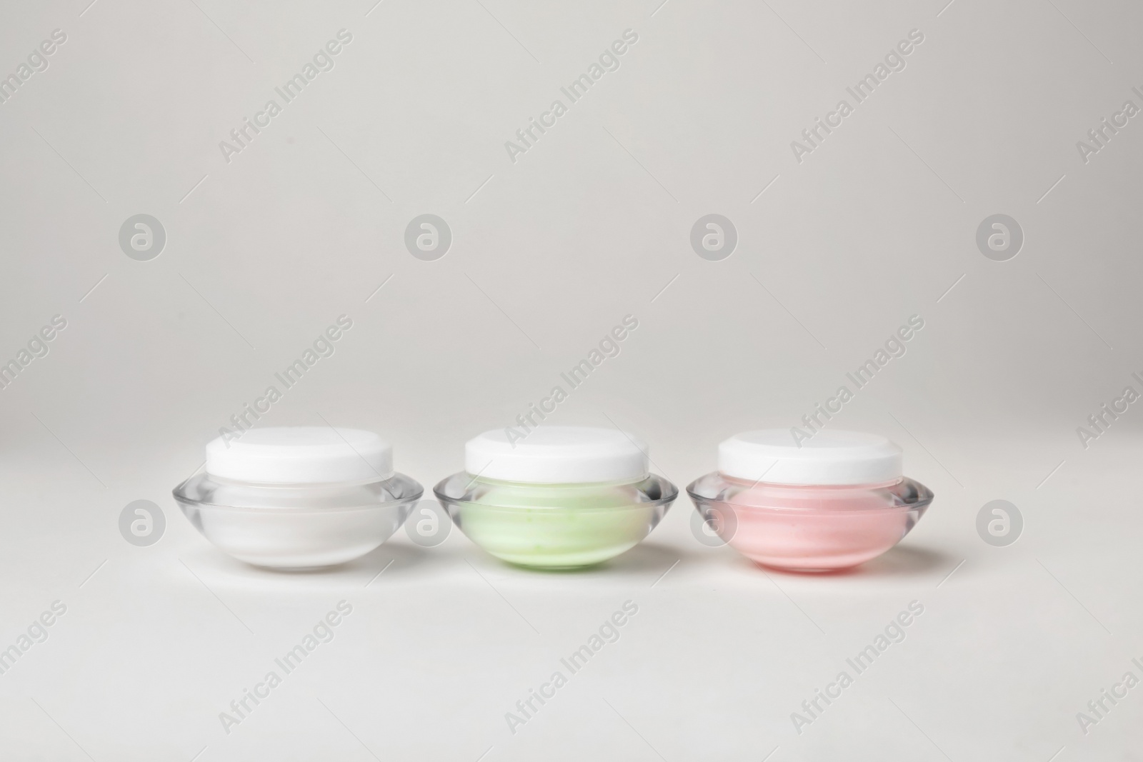 Photo of Jars of cosmetic products on light background