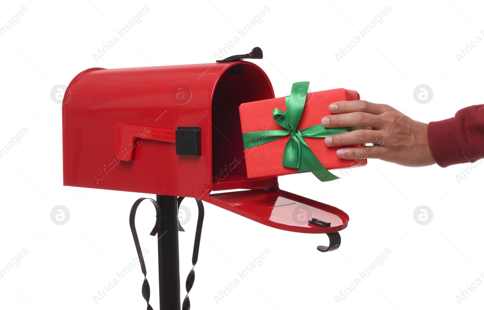 Photo of Man putting Christmas gift into mailbox on white background, closeup. Sending present by mail