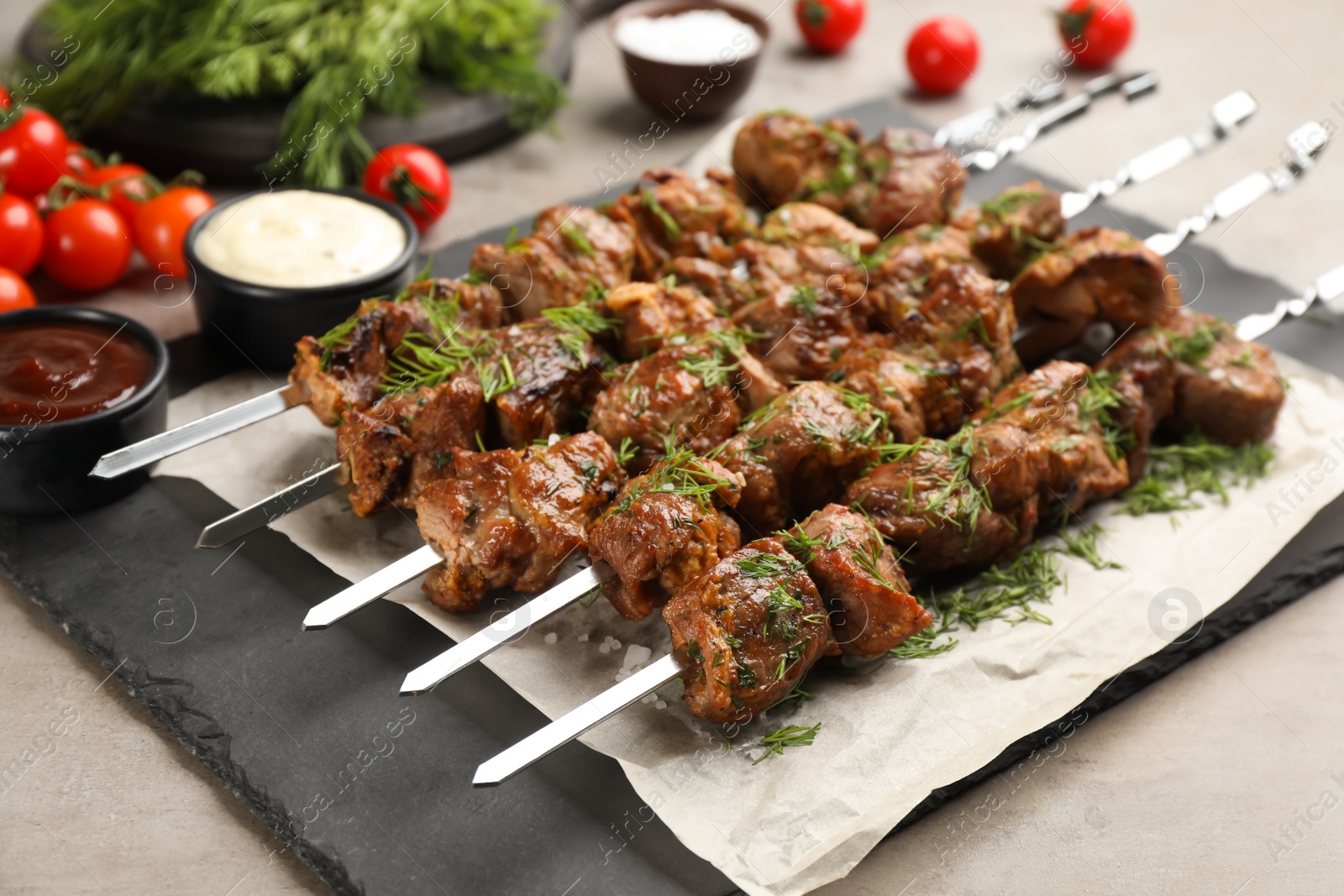 Photo of Metal skewers with delicious meat served on light grey table