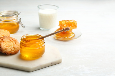 Photo of Fresh honey and cookies on white table. Space for text