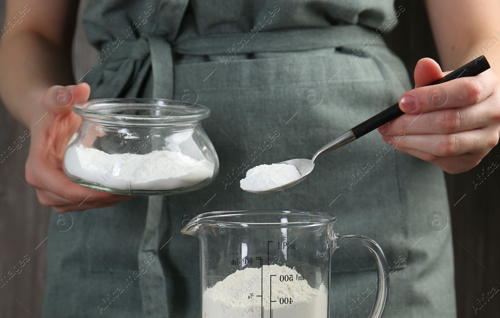 Photo of Woman adding baking powder into measuring cup, closeup