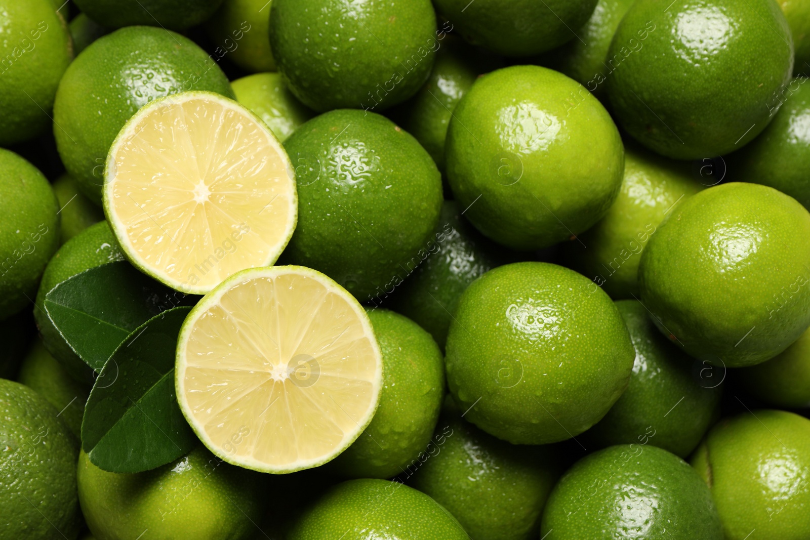 Photo of Fresh limes and leaves with water drops as background, top view