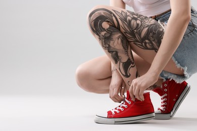 Photo of Woman with cool tattoos on grey background, closeup. Space for text