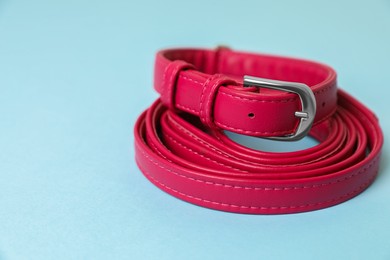 Photo of Red leather dog leash on light blue background, closeup. Space for text