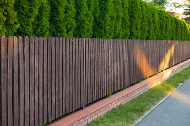 Photo of Green trees behind beautiful wooden fence outdoors