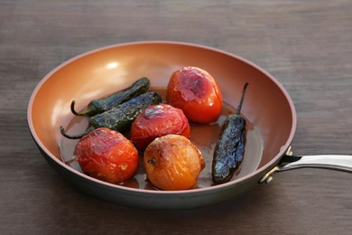 Photo of Frying pan with ingredients for salsa sauce on wooden table