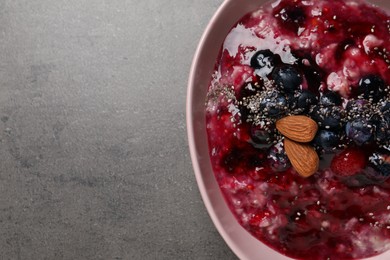 Photo of Tasty oatmeal porridge with toppings on grey table, top view. Space for text