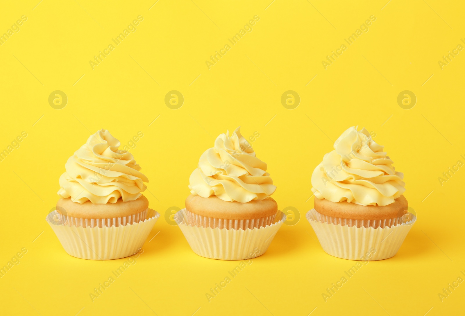 Photo of Tasty cupcakes with cream on yellow background