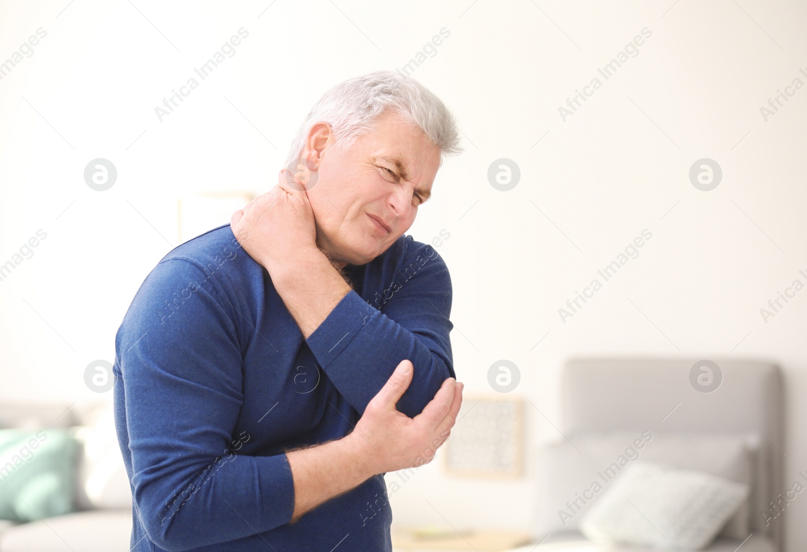 Photo of Mature man suffering from neck pain at home