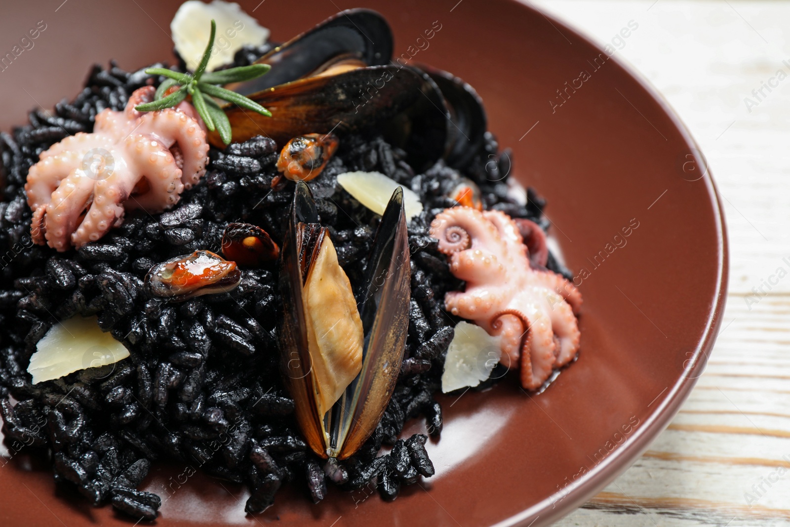 Photo of Delicious black risotto with seafood on white wooden table, closeup