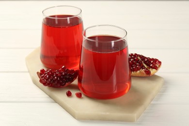 Photo of Tasty pomegranate juice in glasses and fresh fruit on white wooden table
